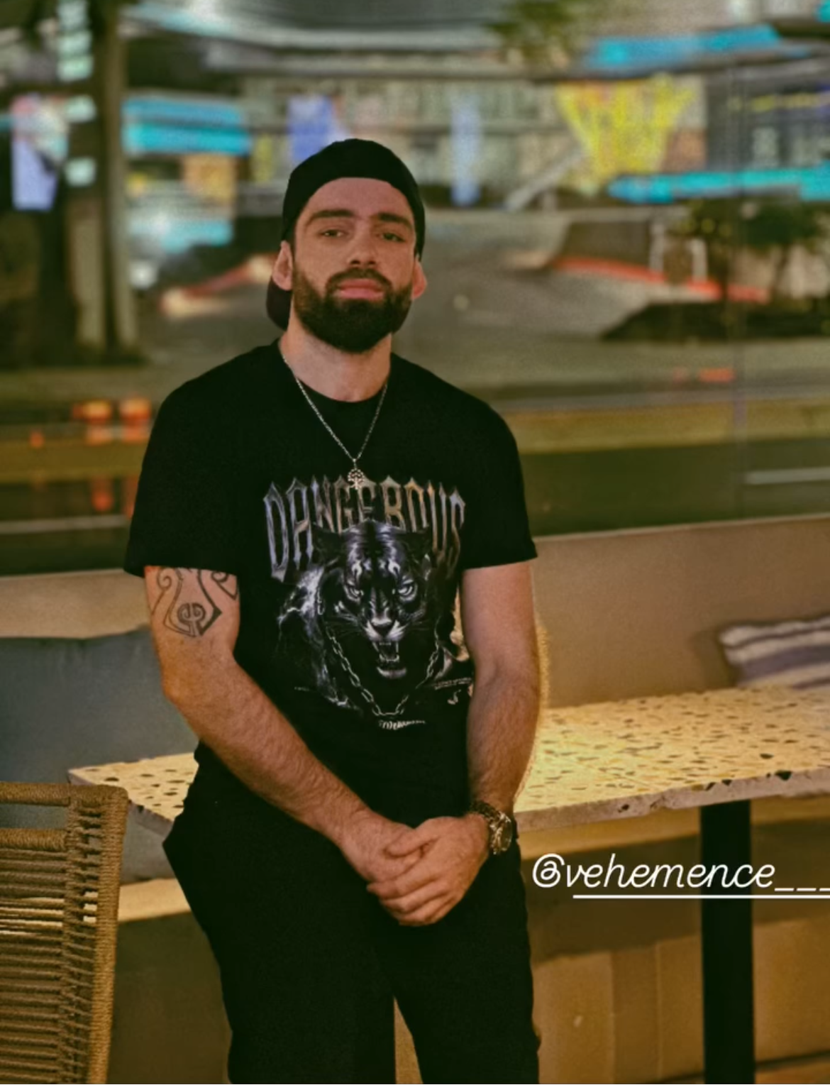 Male 5'6 wearing a black t-shirt with 'Dangerous' printed on it, standing in an urban setting.